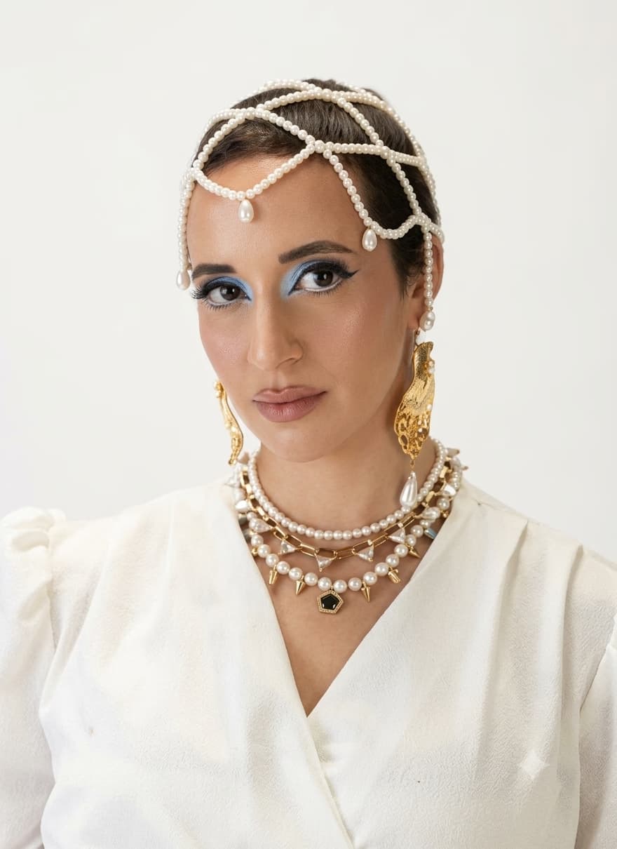 Editorial makeup look by Elani, Dubai makeup artist — blue graphic eyeshadow, pearl headpiece and layered gold jewellery for a fashion shoot